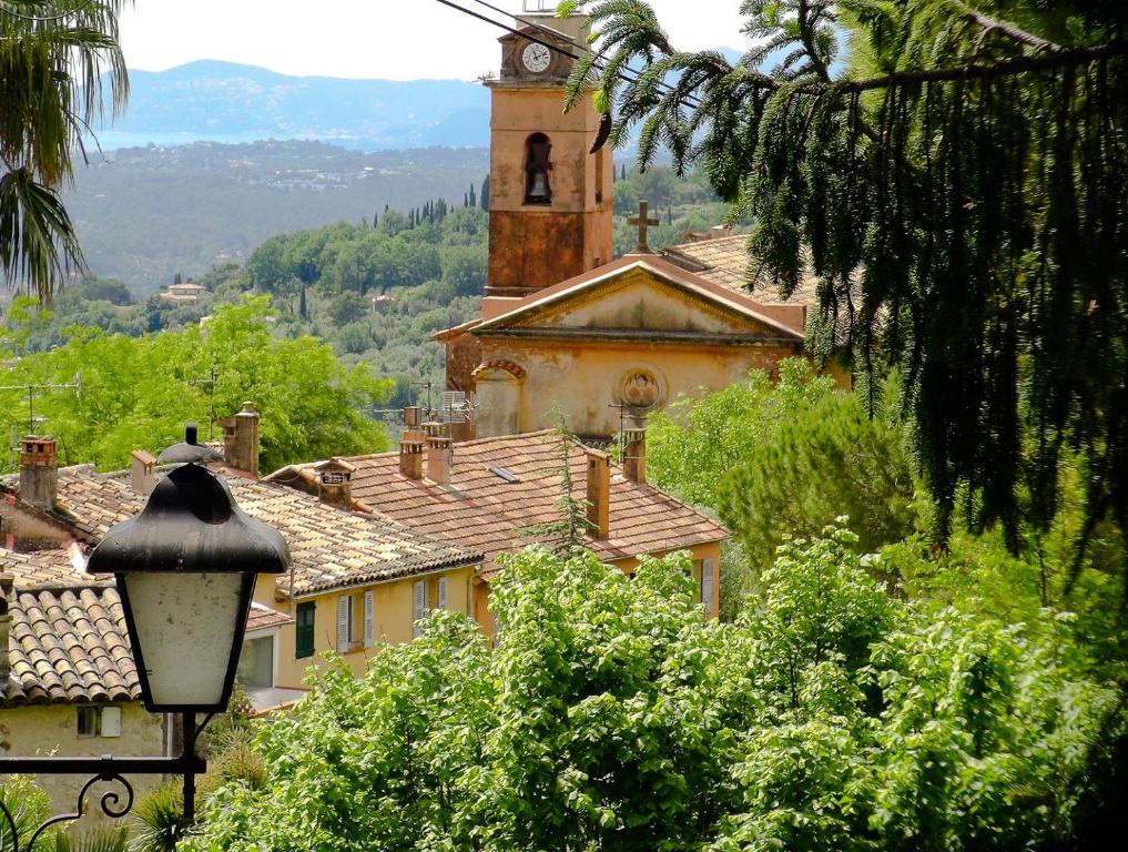 un vieux bâtiment avec une tour d'horloge dans un village dans l'établissement Charmant appartement dans maison de village, à Magagnosc