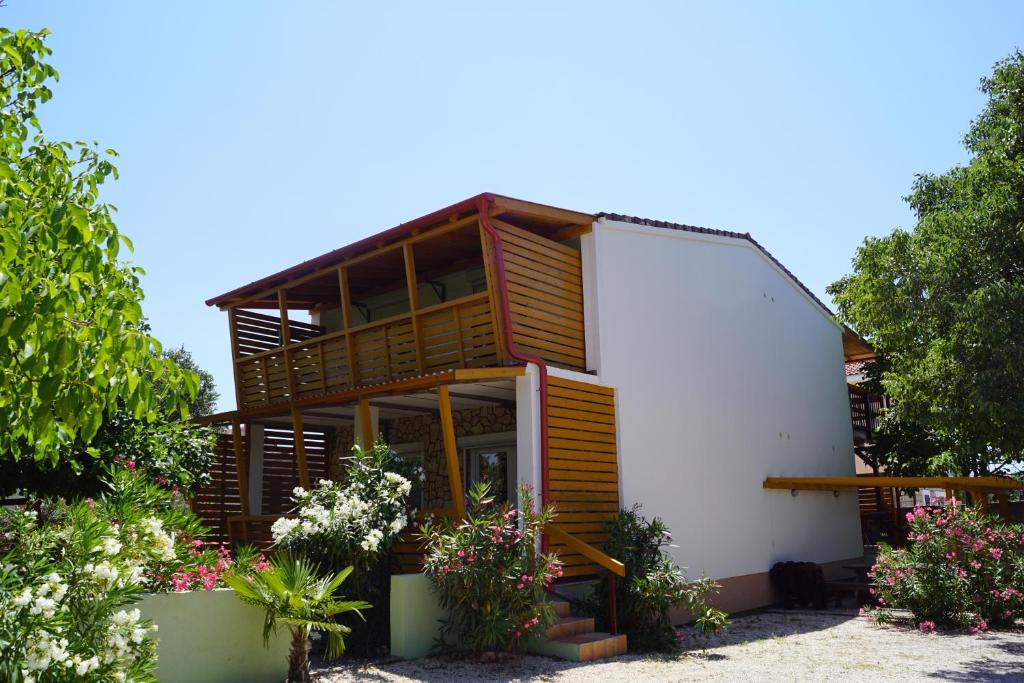 a house with wooden windows and flowers in front of it at Pirovac - most beautiful beaches in Dalmatia in Pirovac