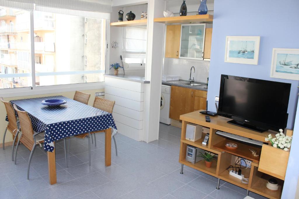 een woonkamer met een tafel en een keuken met een televisie bij BRAVAHOLIDAYS-121-Canastell-58 in Blanes