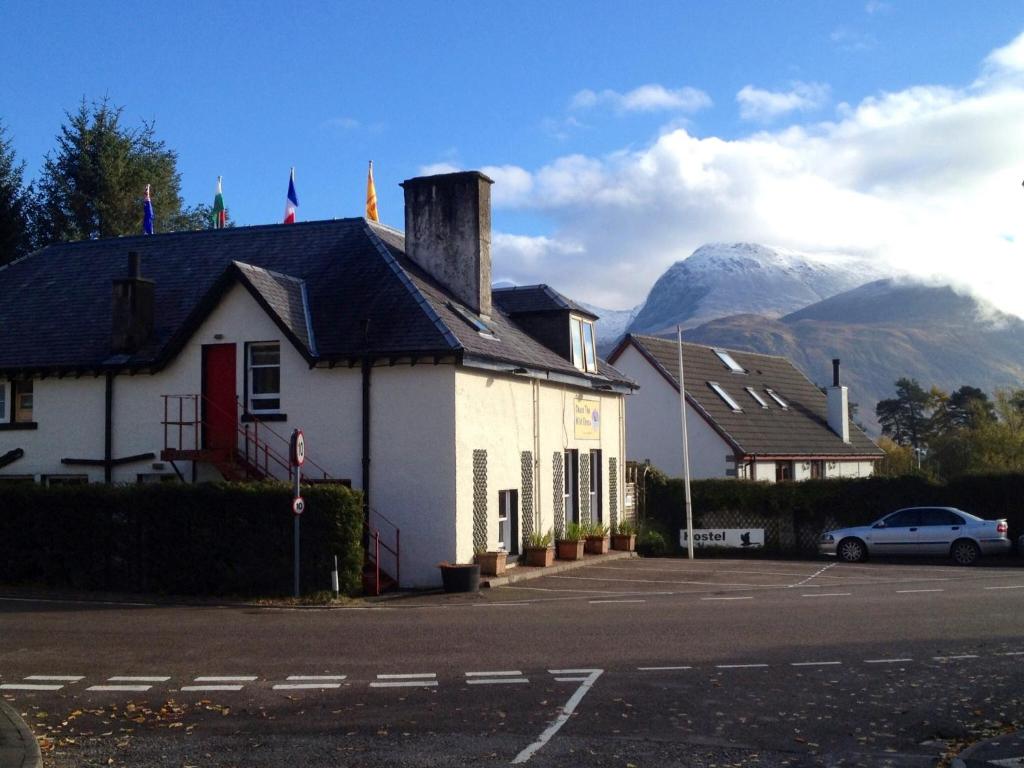 a white building with a mountain in the background at Chase the Wild Goose in Fort William