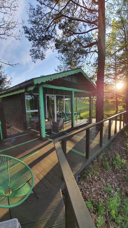 une terrasse en bois avec un bâtiment avec un arbre dans l'établissement VIP Green House of Hope for 2, à Leliūnai