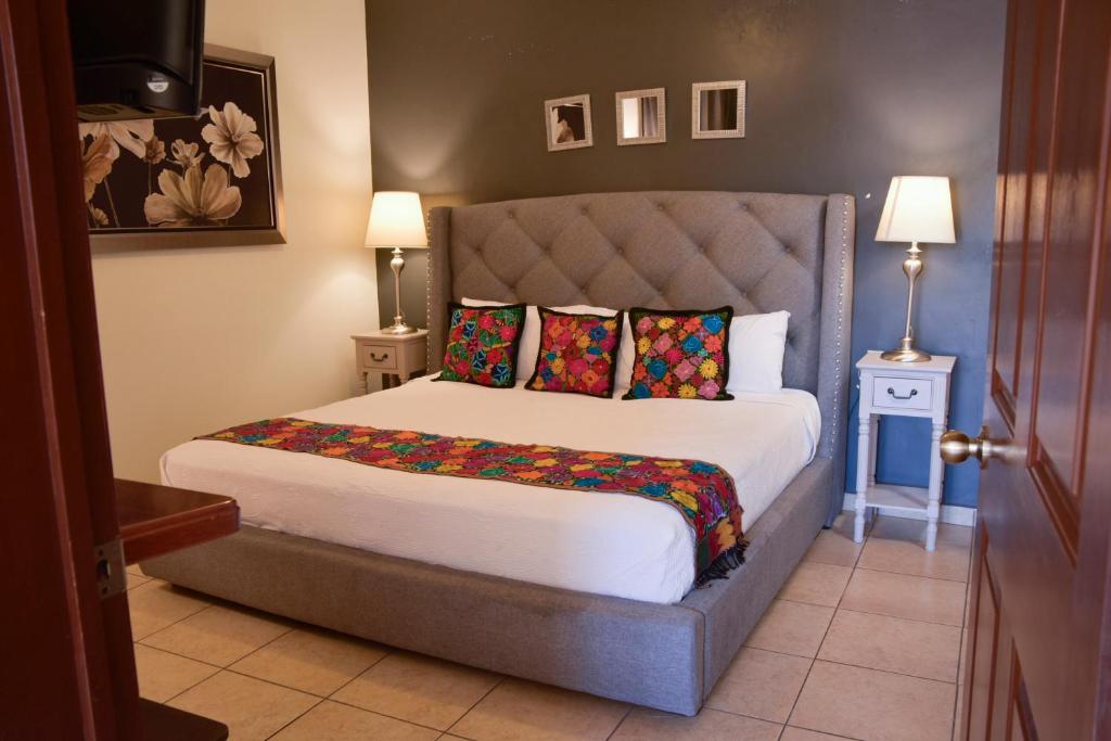 a bedroom with a large bed with colorful pillows at Del Centro Hotel Bernal in Bernal
