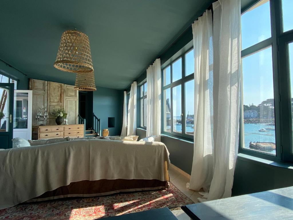 ein Schlafzimmer mit einem großen Bett und großen Fenstern in der Unterkunft La maison du grand rocher in Ploubazlanec