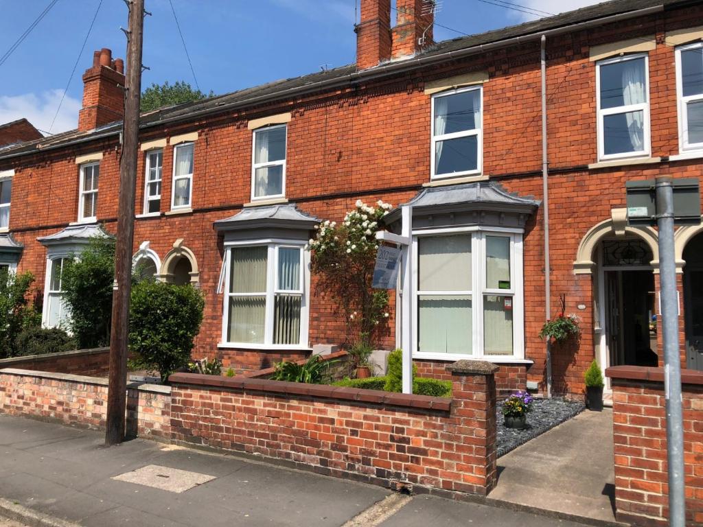 a red brick house with white windows and plants at 202 Guesthouse in Lincoln