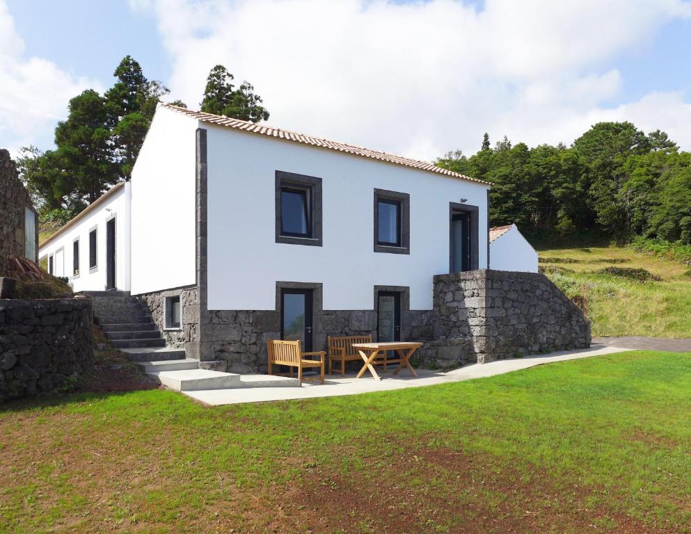 una casa blanca con una mesa delante en Areias da Prainha, en Prainha de Cima