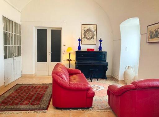 - un salon avec deux chaises rouges et un piano dans l'établissement IL TRAPPETO B&B, à Laterza