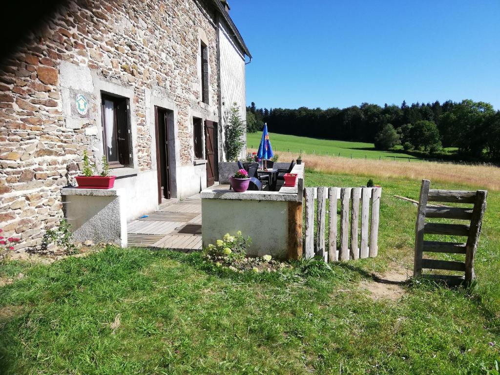 - un bâtiment en pierre avec une terrasse couverte et une clôture en bois dans l'établissement gite les chaumeix, à Prondines