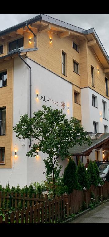 a building with a tree in front of it at Quality Hosts Arlberg - ALPtyrol Appartements in Sankt Anton am Arlberg
