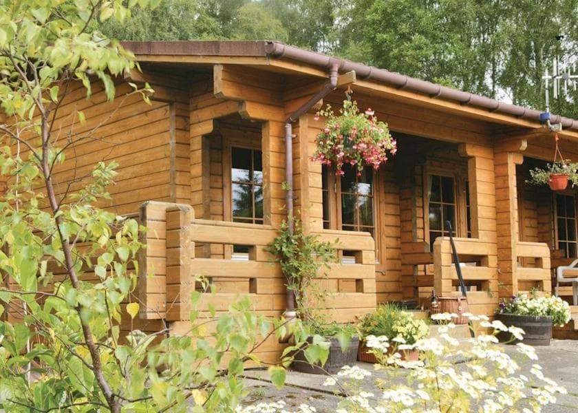 une cabane en rondins avec une fleur suspendue dans l'établissement Cosy & compact Rowan Lodge no4, à Killin