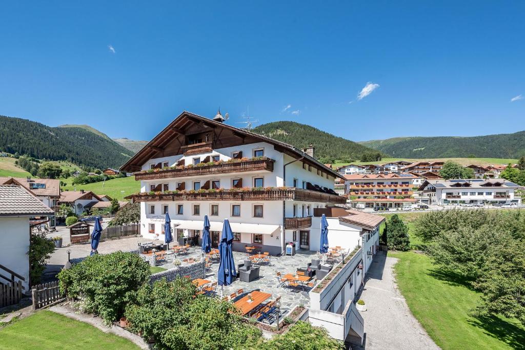 a view of a building with umbrellas and chairs at Hotel Wiedenhofer in Terento