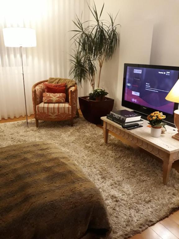uma sala de estar com uma televisão, uma cadeira e uma mesa em Casa de Leça em Leça da Palmeira