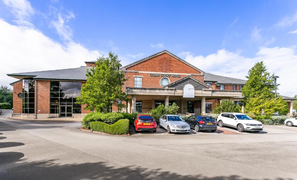 un bâtiment avec des voitures garées dans un parking dans l'établissement Cedar Court Bradford Hotel, à Bradford