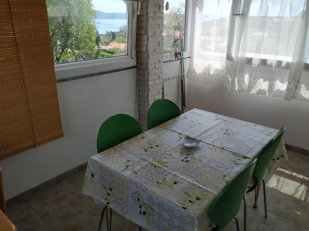 a table with green chairs in a room with a window at Apartment Anka in Savar