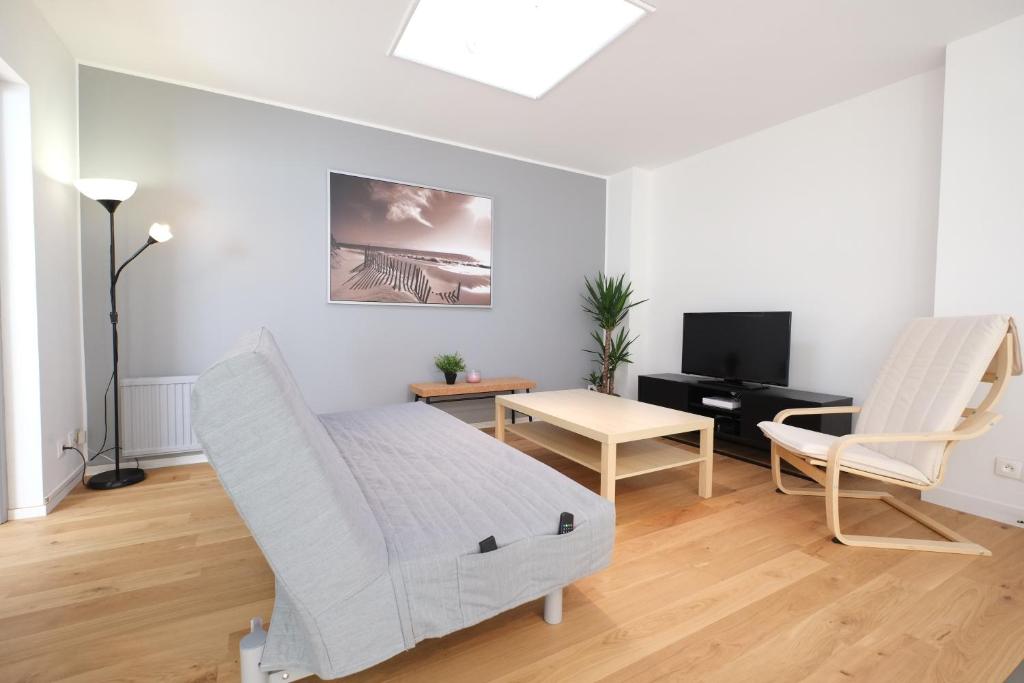 a white room with a bed and a table and a tv at Escale de 80 m2 avec cour et parking in Lille