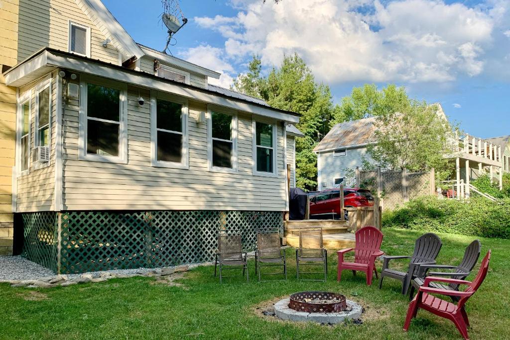 ein Haus mit Stühlen und einer Feuerstelle im Hof in der Unterkunft Jay Peak Getaway on Trout River in Montgomery