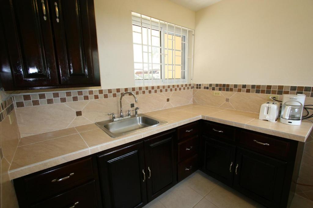 una cocina con armarios negros y fregadero en White Sands Negril, en Negril