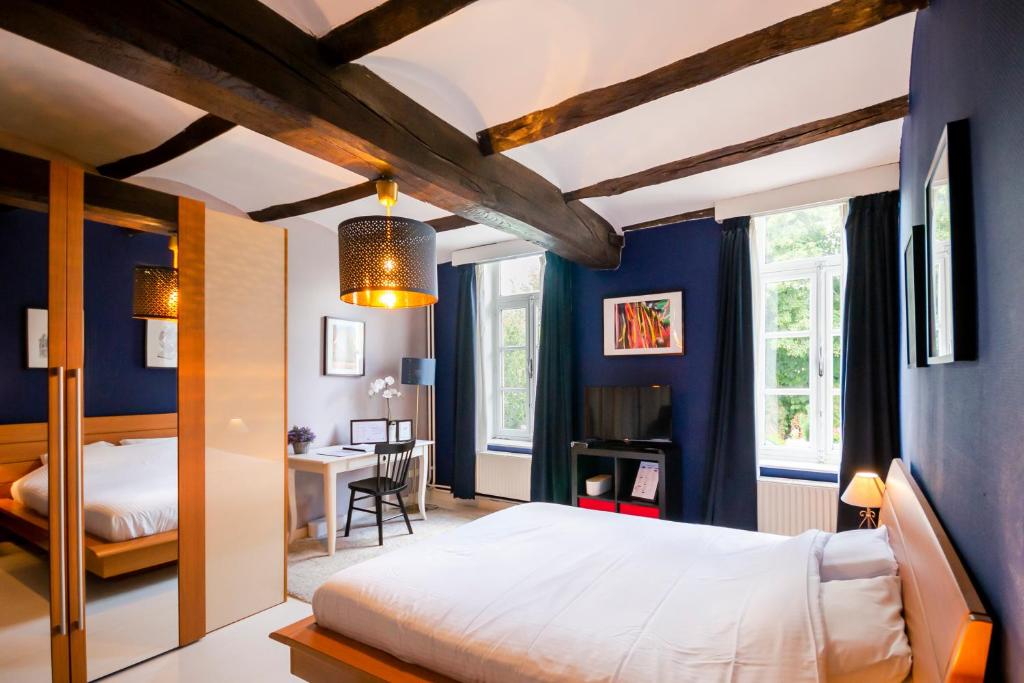 Au Petit Dragon في مون: غرفة نوم بجدران زرقاء وسرير ومكتب
