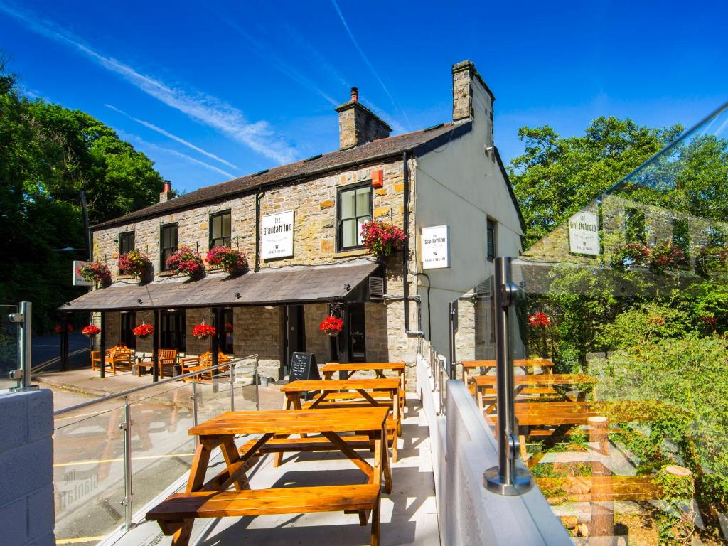 una fila de mesas de madera frente a un edificio en The Glantaff Inn Bunkhouse en Treharris