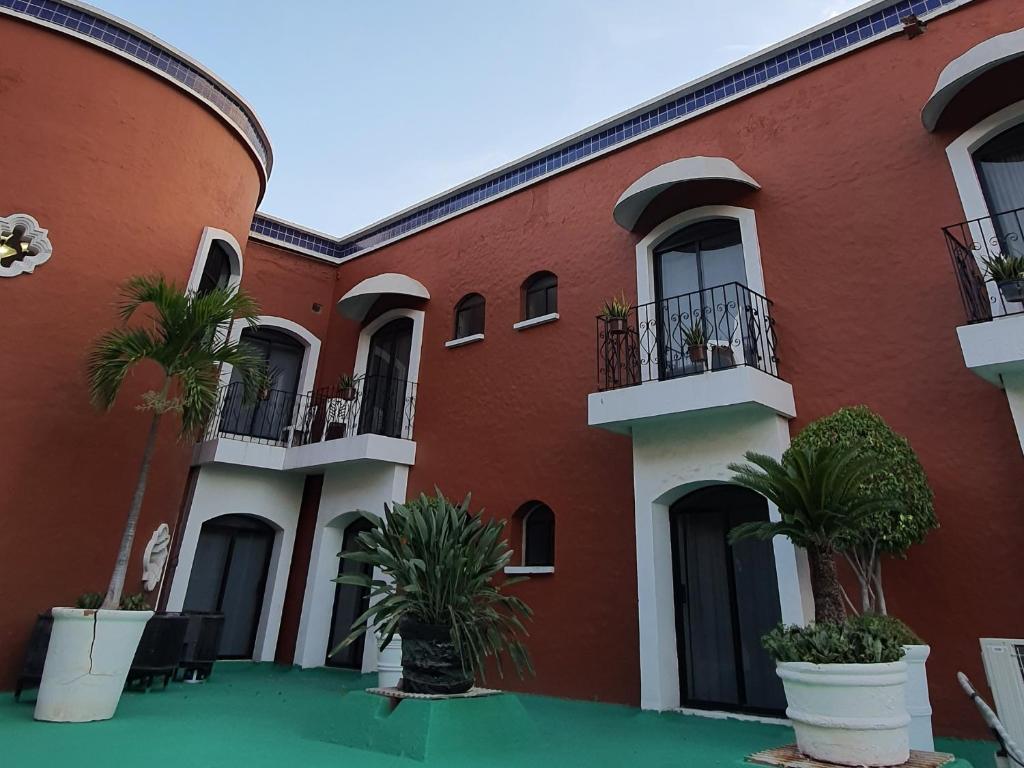 un bâtiment rouge avec des plantes devant lui dans l'établissement Hotel el Mayo Inn, à Culiacán