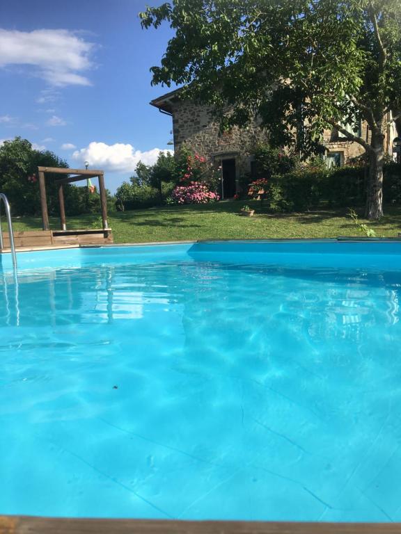 a large blue swimming pool with a stone house in the background at Il Mugello B&B in Vicchio