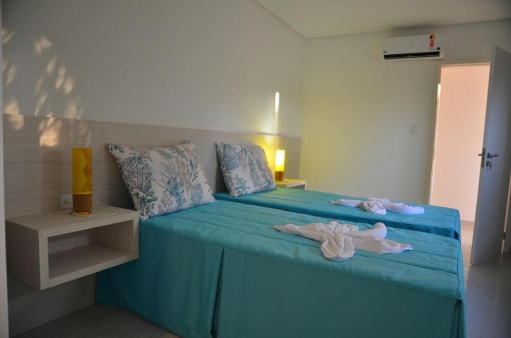 Un dormitorio con una cama azul con muñecas. en Oásis do Sol, en Porto de Galinhas