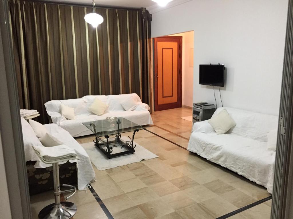 a living room with two white couches and a television at Belaire host appartment in Boumhel El Bassatine