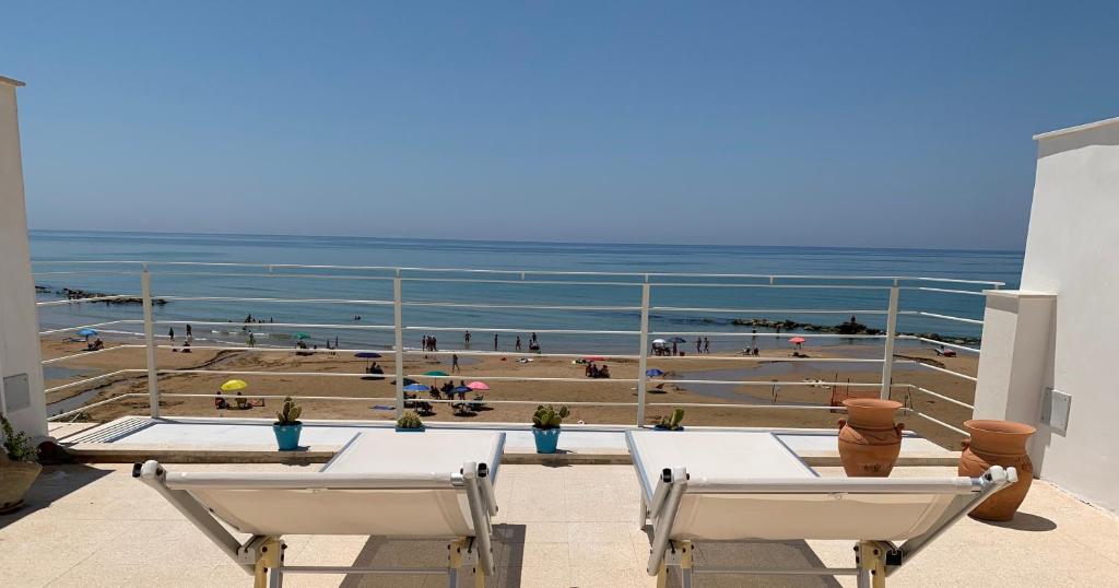 uma varanda com cadeiras e vista para a praia em Donna Teresa appartamenti em Donnalucata