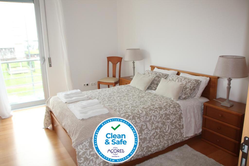 a bedroom with a bed with a sign that says clean and safe at Casa da Juka in Ponta Delgada