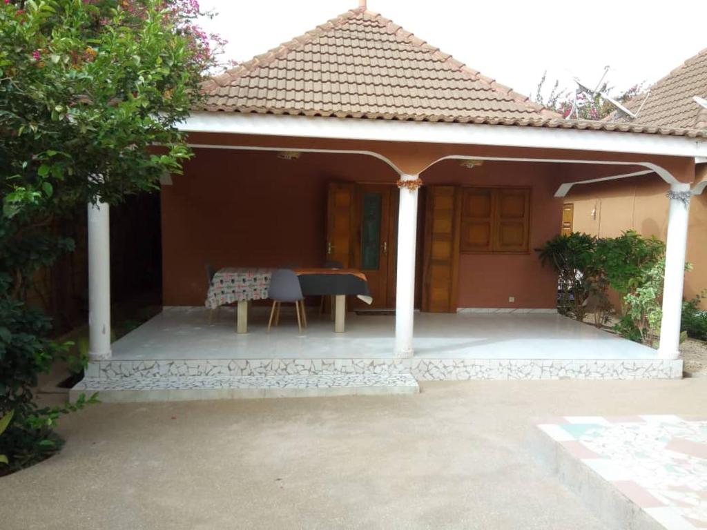 ein kleines Haus mit einer Terrasse mit einem Tisch in der Unterkunft Chez Coumba et Daniel in Saly Portudal