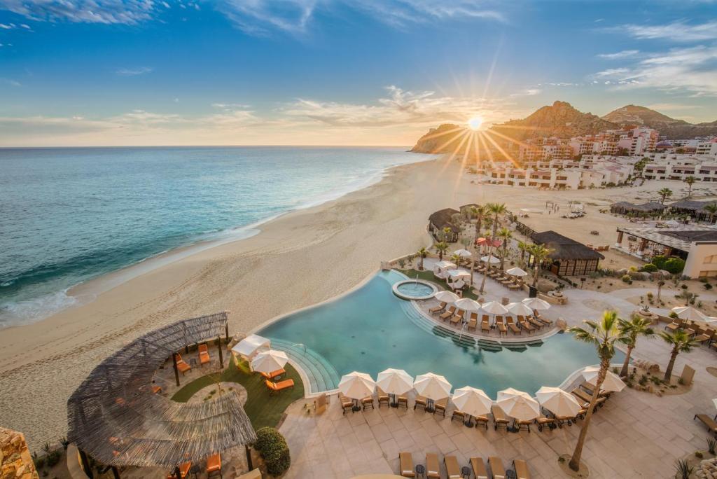 a beach filled with lots of beach chairs and umbrellas at Grand Solmar Land's End Resort & Spa in Cabo San Lucas