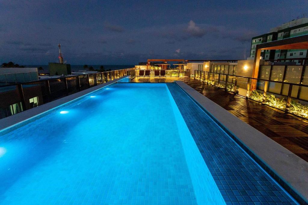 a swimming pool on the roof of a building at night at Eco Summer Tambaú - Apartamentos de 2 Quartos por Genius Flats in João Pessoa