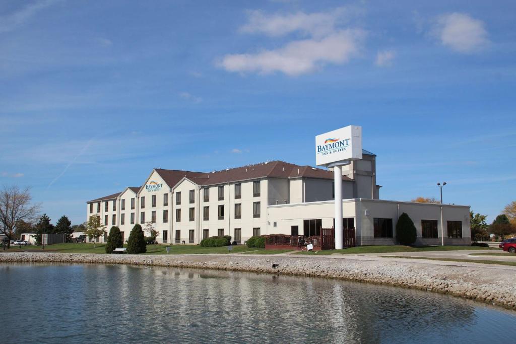 a large white building with a sign next to a body of water at Baymont Inn & Suites by Wyndham Findlay in Findlay