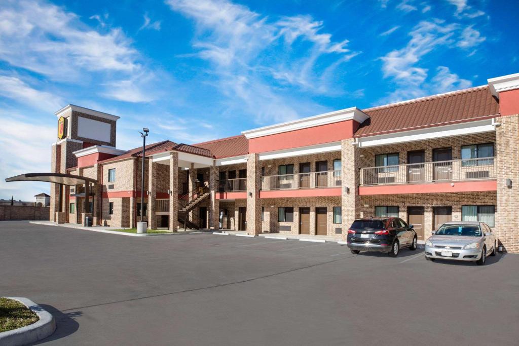 un grand bâtiment avec des voitures garées dans un parking dans l'établissement Super 8 by Wyndham Humble Houston Fallcreek, à Humble