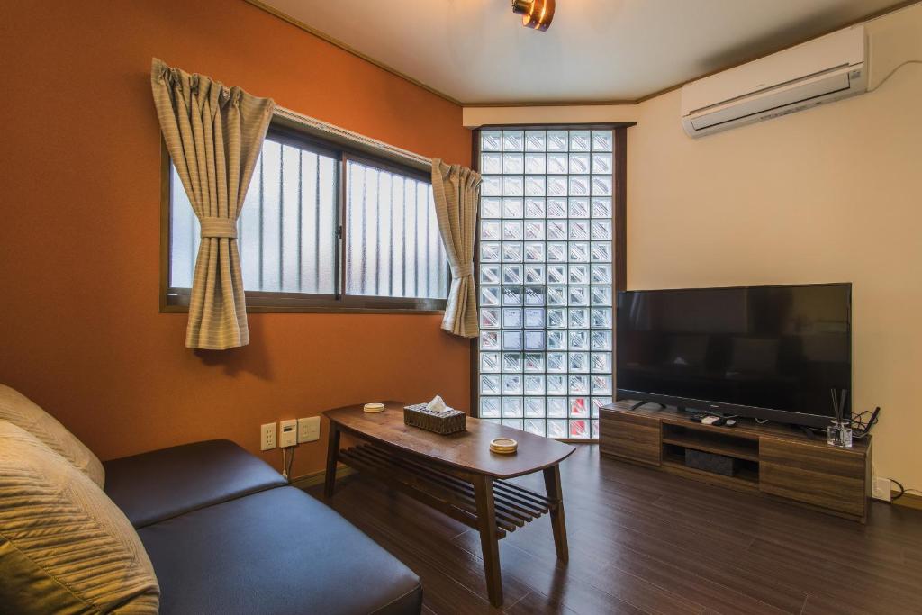 a living room with a couch and a flat screen tv at Shiki Homes KURIKO in Osaka