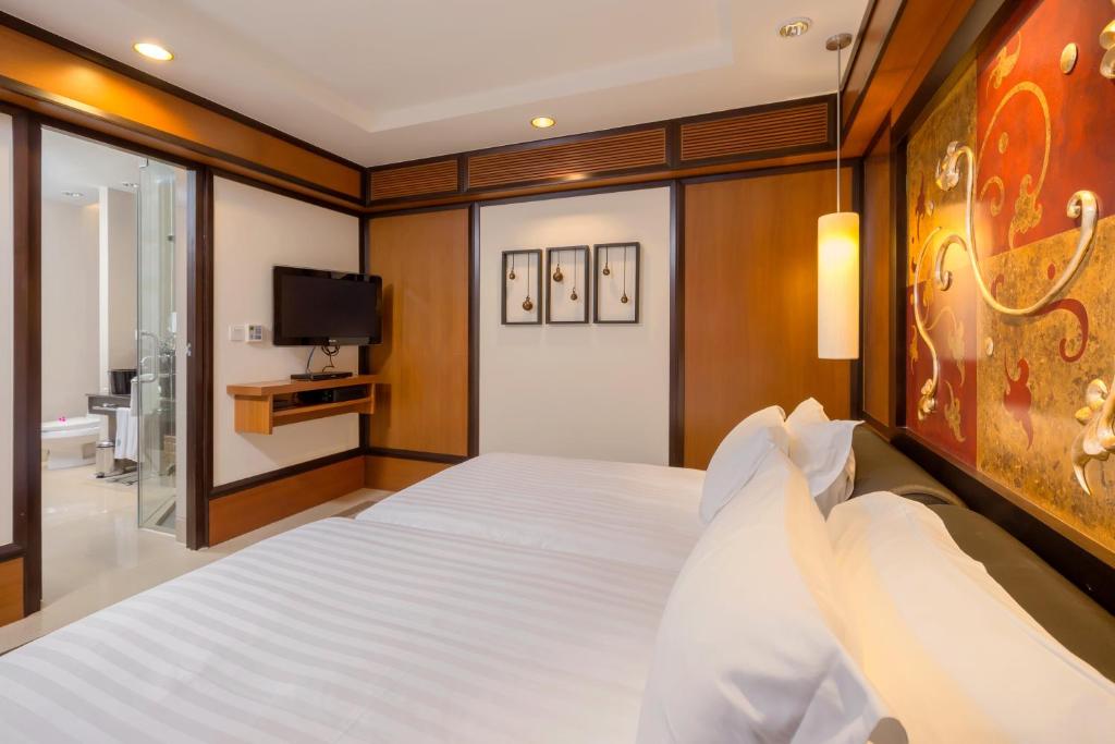a bedroom with a large white bed with a tv at Banyan Tree Phuket in Bang Tao Beach
