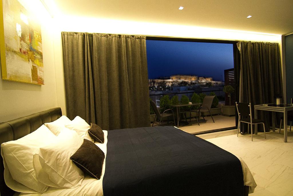 アテネにあるAcropolis Suiteのベッドと大きな窓が備わるホテルルームです。