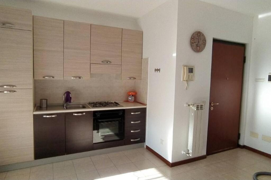 a kitchen with brown cabinets and a clock on the wall at LA SISTEMAZIONE BRILLANTINO TITANIUM in Rozzano