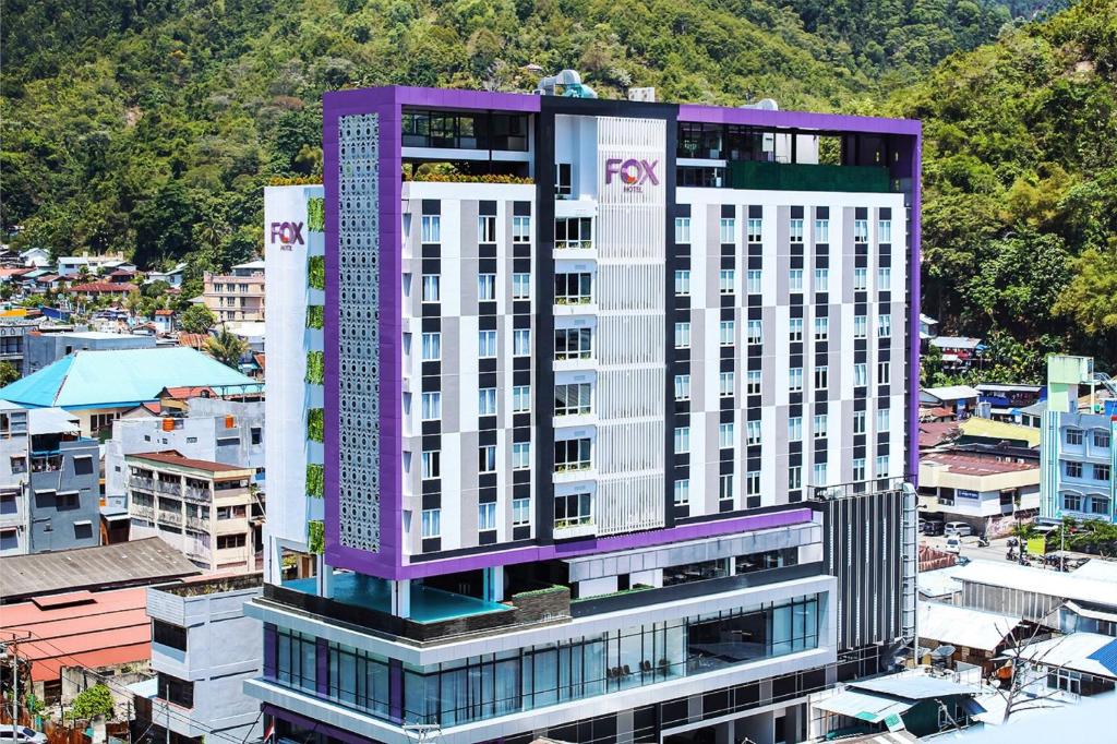 a tall purple and white building in a city at Fox Hotel Jayapura in Jayapura