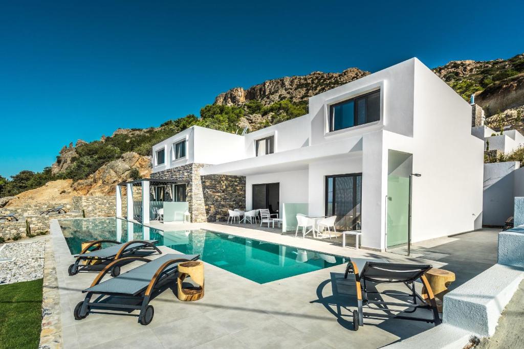 uma casa branca com piscina e cadeiras em Villa Daniela & Apartments em Koutsounari