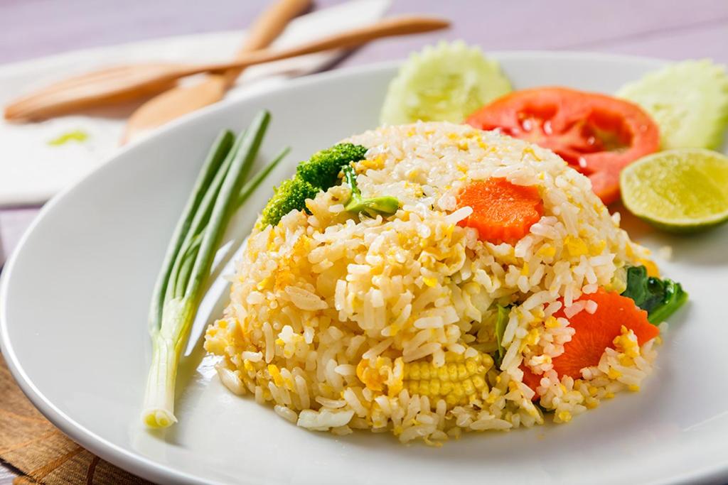 une plaque blanche avec du riz et des légumes sur une table dans l'établissement DAYA hill seaview, à Koh Lipe