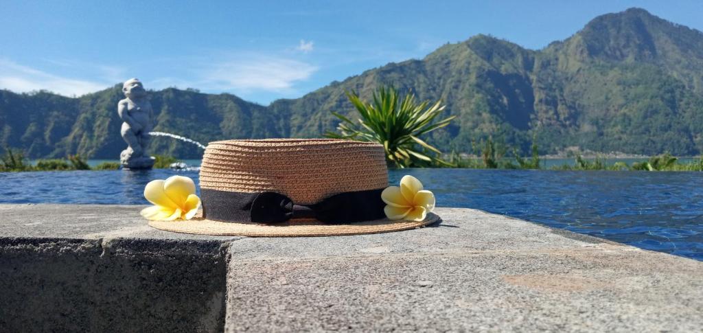 un sombrero de paja con flores amarillas sentadas en una pared en Lakeside Log Cabins, en Kintamani