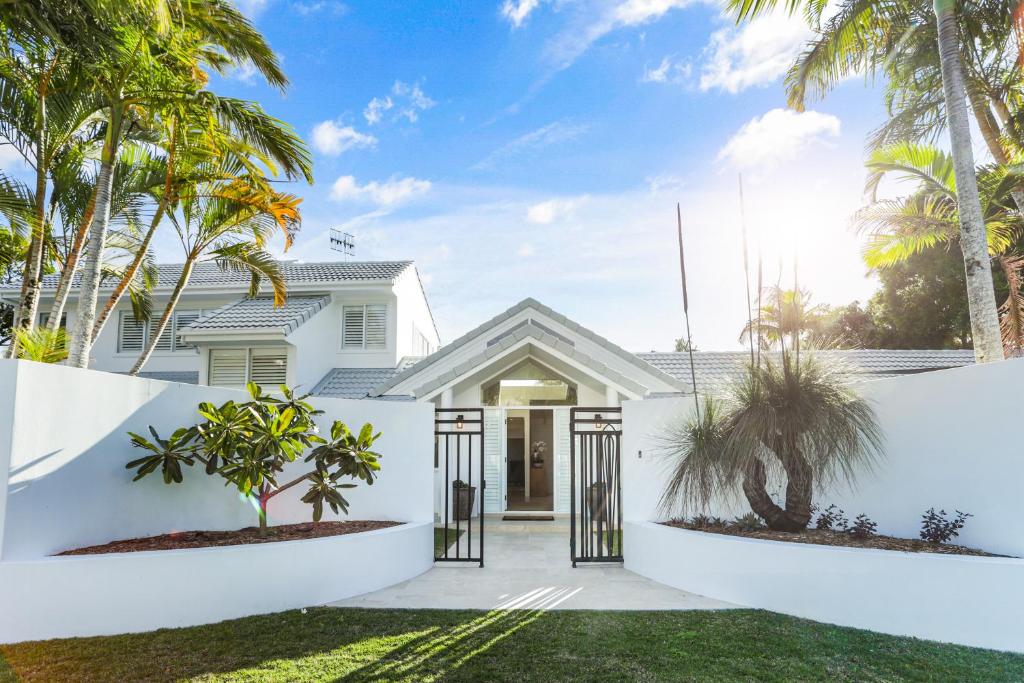 a white house with palm trees in the front yard at Island living in the heart of Noosa in Noosa Heads