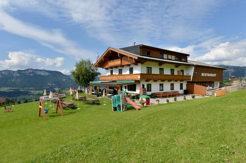 een groot gebouw met een speeltuin in een veld bij Alpengasthof Hirschberg in Sankt Johann in Tirol