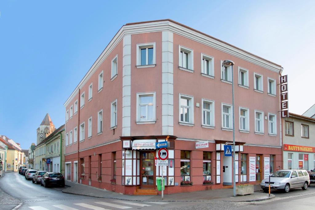 een gebouw in een straat waar auto's voor geparkeerd staan bij Hotel zur Sonne in Korneuburg