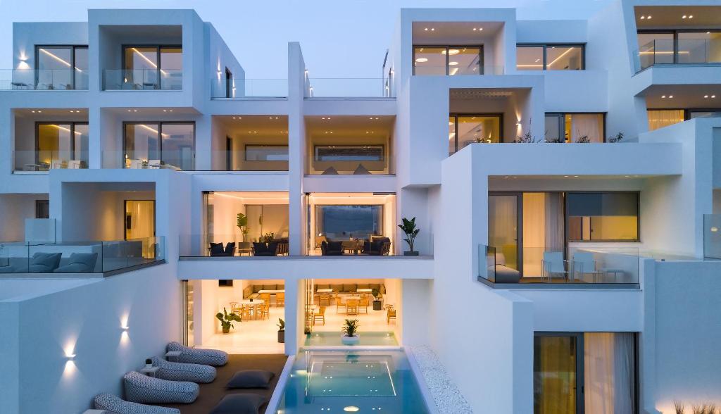 un grand bâtiment blanc avec une piscine dans l'établissement Infinity View Hotel Tinos, à Tinos
