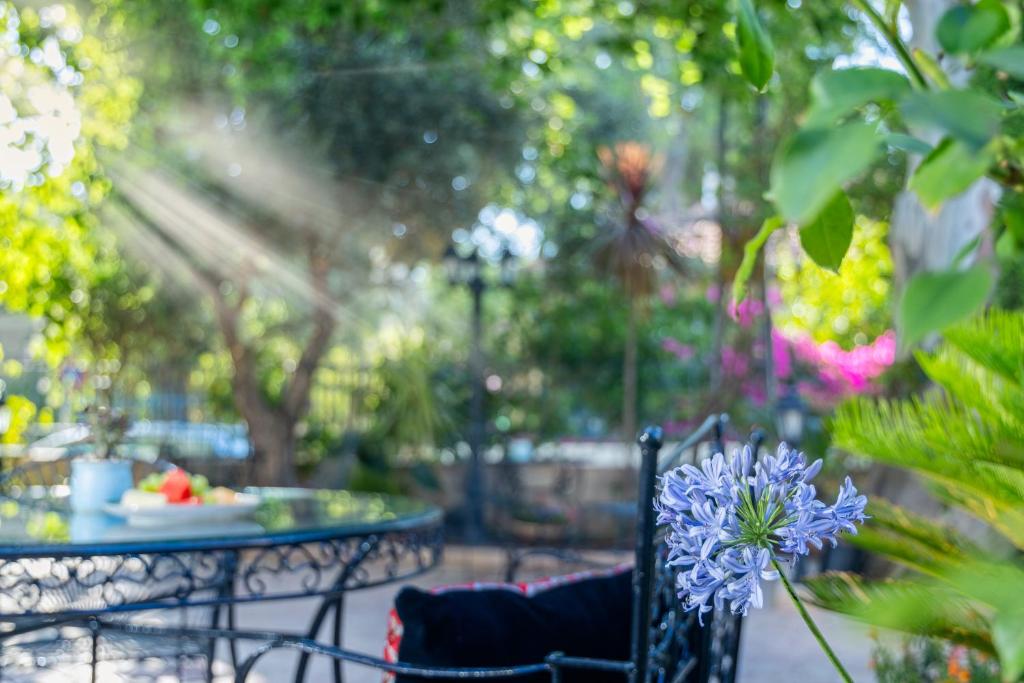 a table and chairs in a garden with a blue flower at Villa Brown Moshava - a member of Brown Hotels in Jerusalem