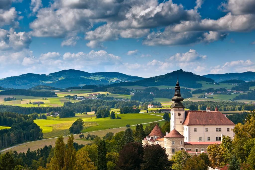 a church on a hill with mountains in the background at Schloss Weinberg in Kefermarkt