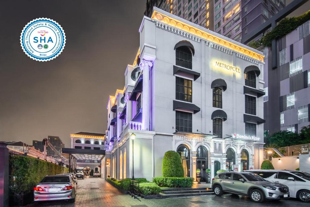 a white building with cars parked in front of it at Metropole Bangkok in Bangkok