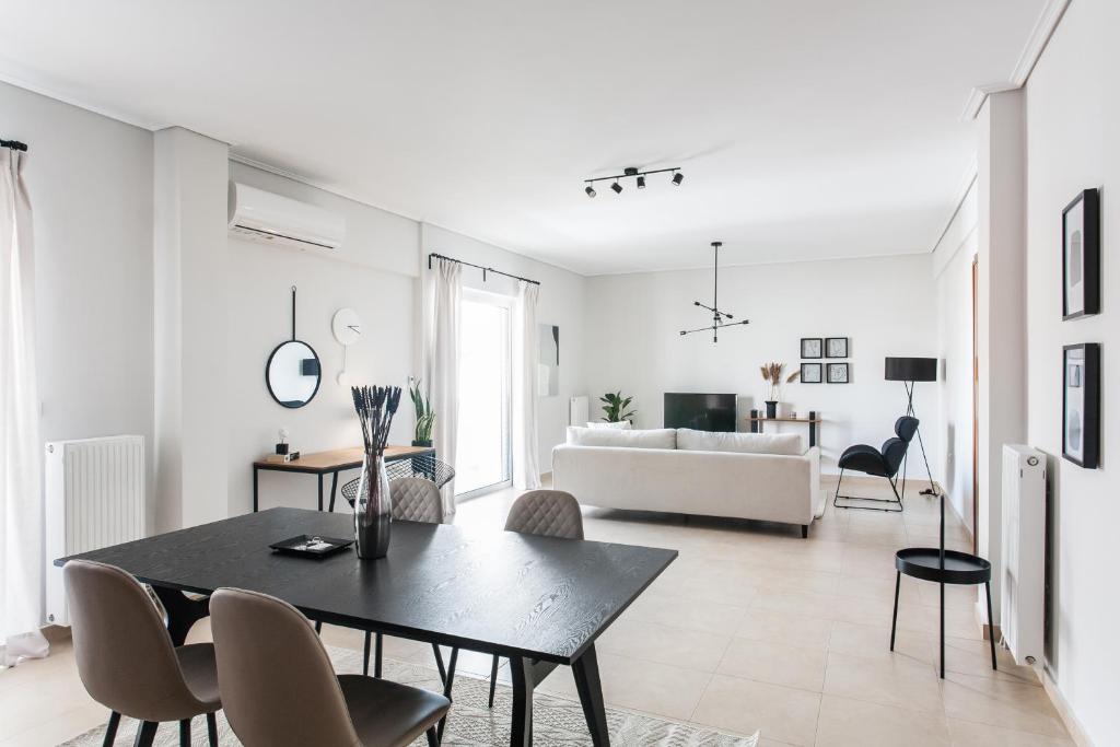 a white living room with a black table and chairs at Superb & Comfy 2BD Apartment in Marousi by UPSTREET in Athens