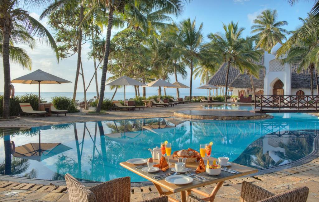 uma mesa com comida fica ao lado de uma piscina num resort em Sultan Sands Island Resort em Kiwengwa